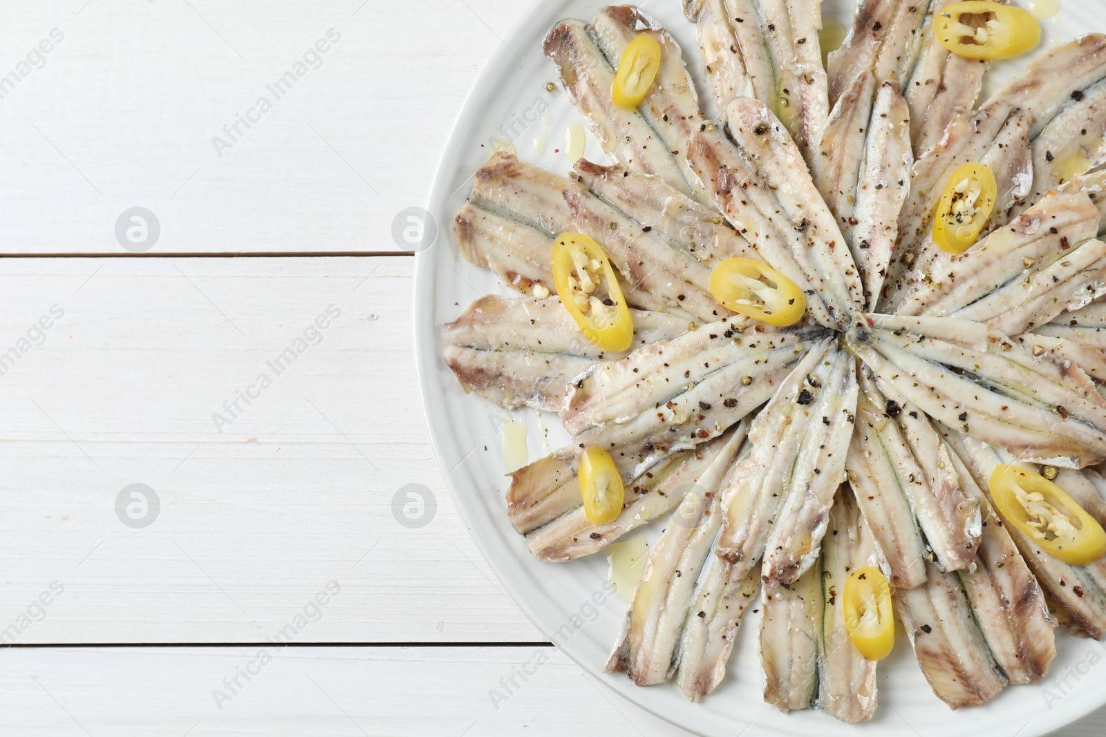 Photo of Tasty pickled anchovies with spices on white wooden table, top view. Space for text