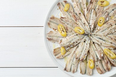 Photo of Tasty pickled anchovies with spices on white wooden table, top view. Space for text