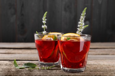 Photo of Glasses of delicious refreshing sangria on old wooden table