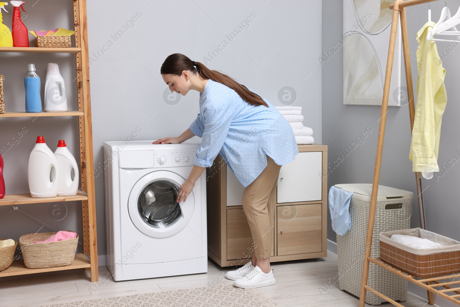 Photo of Beautiful woman near washing machine in laundry room