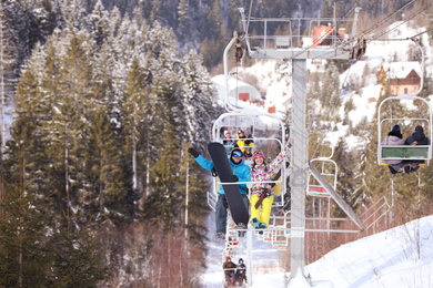 Photo of Couple using chairlift at mountain ski resort. Winter vacation