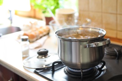 Photo of Shiny pot with boiling water on stove indoors. Space for text