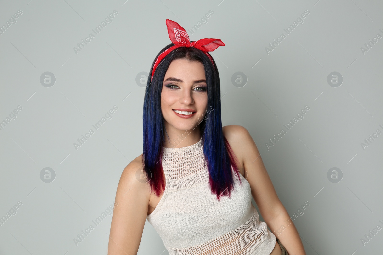 Photo of Young woman with bright dyed hair on light background