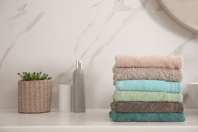 Photo of Stack of fresh towels on white countertop in bathroom