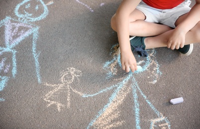 Little child drawing family with chalk on asphalt