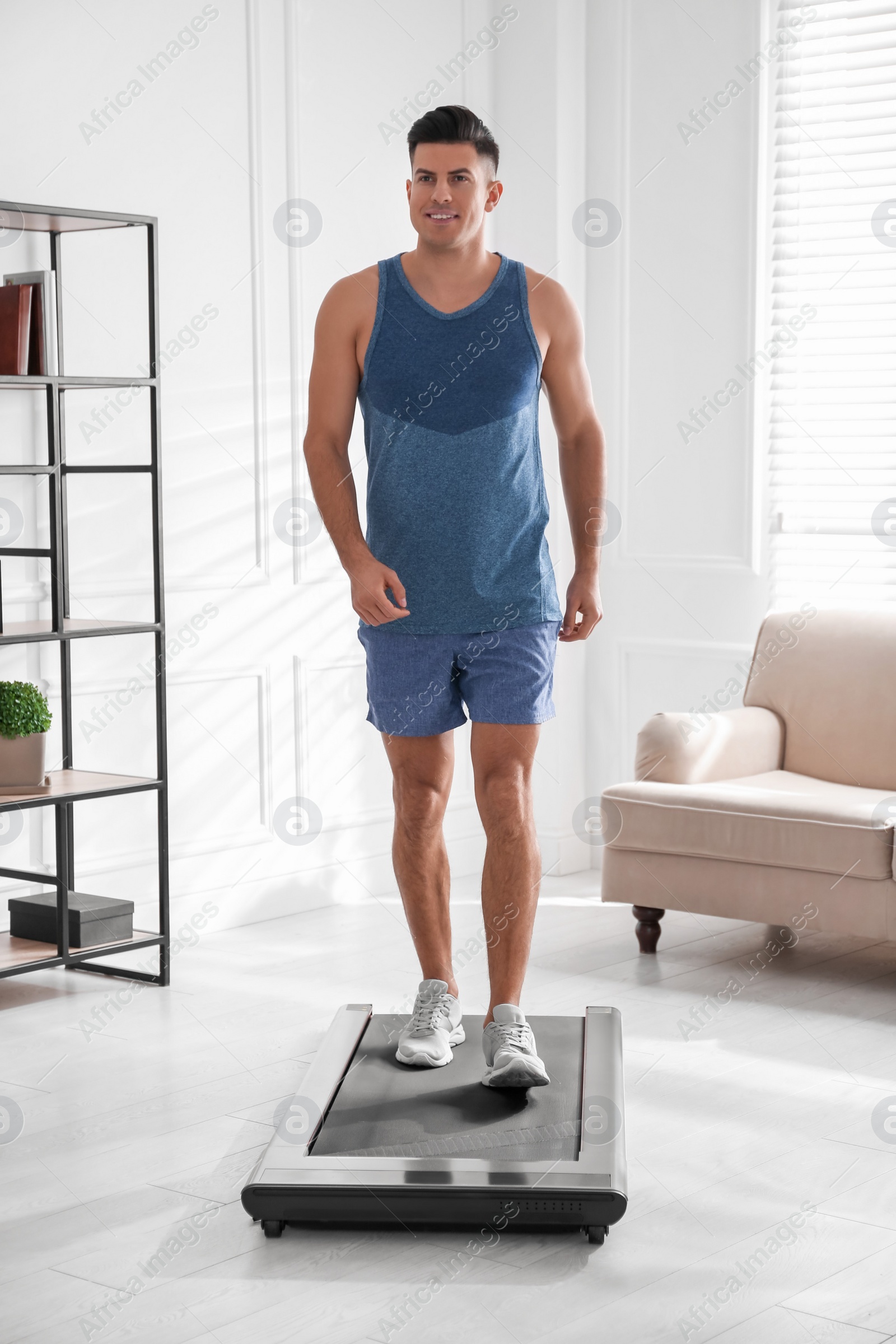 Photo of Sporty man training on walking treadmill at home