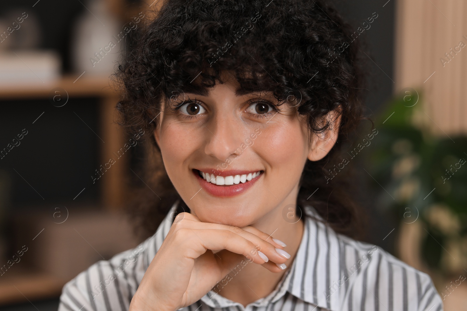 Photo of Portrait of beautiful woman with curly hair indoors. Attractive lady smiling and looking into camera