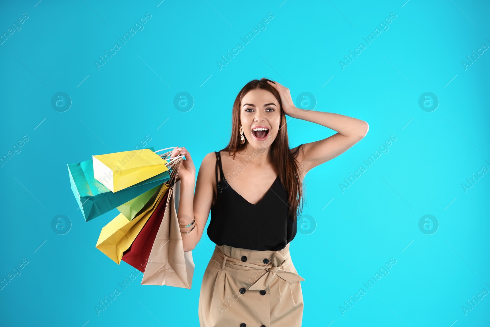 Photo of Young woman with shopping bags on color background