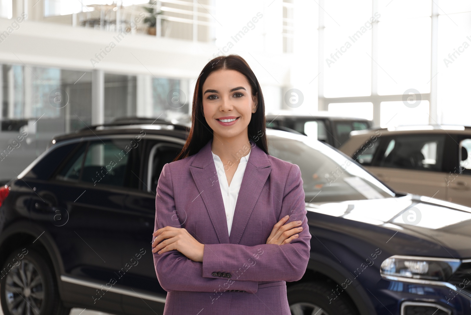 Photo of Happy young saleswoman in modern car salon