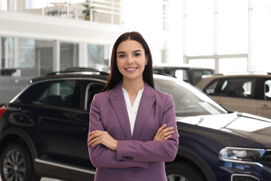 Happy young saleswoman in modern car salon