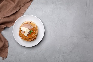 Plate with tasty pancakes on grey background, top view