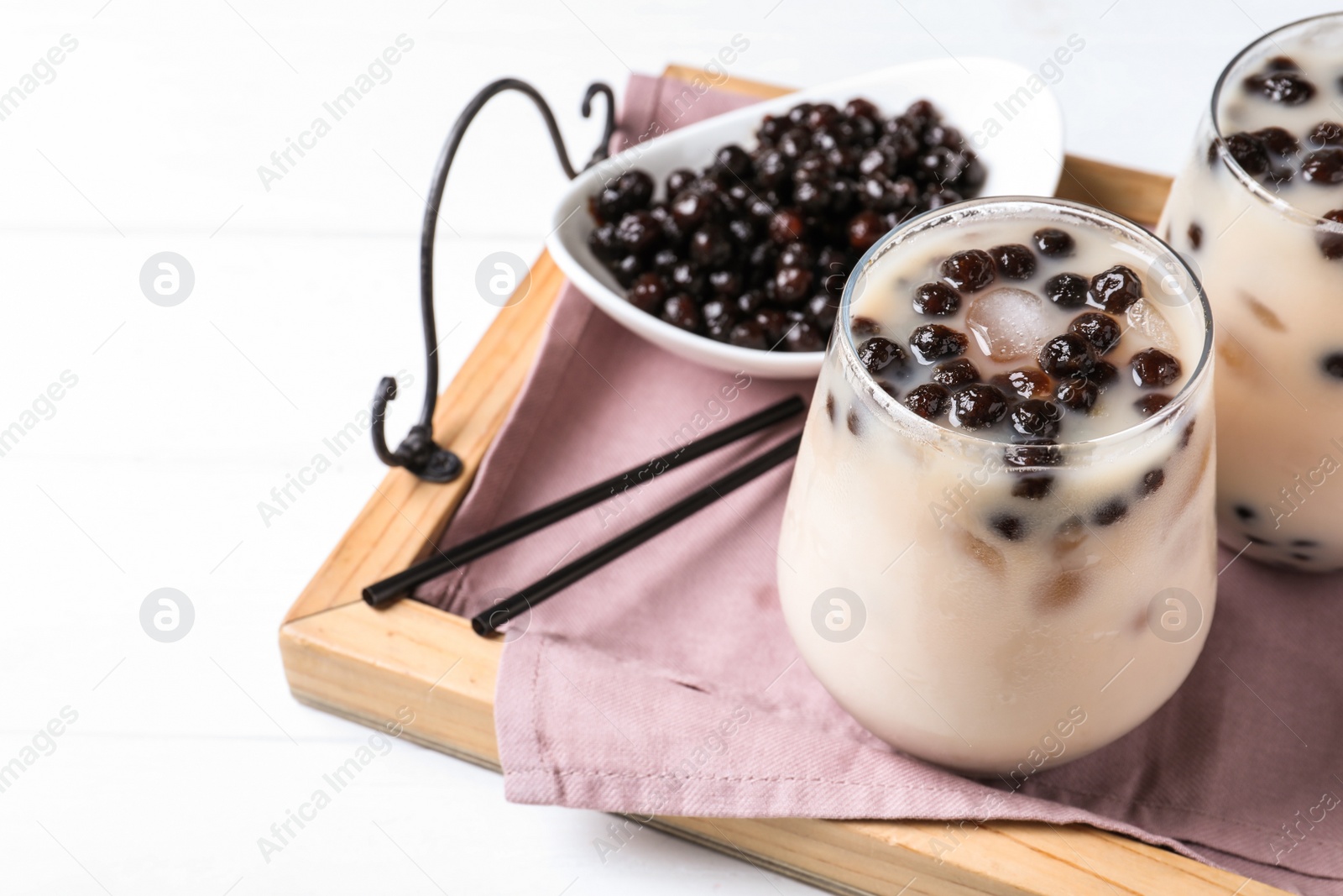 Photo of Bubble milk tea with tapioca balls on wooden tray