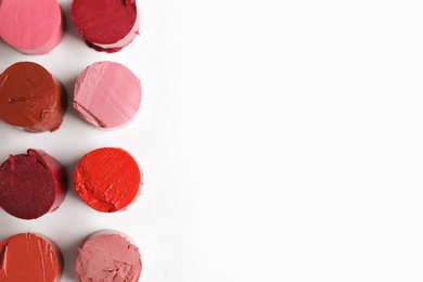 Photo of Different lipstick swatches on white background, top view