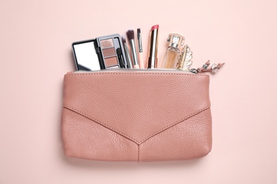 Photo of Makeup products with cosmetic bag on pink background