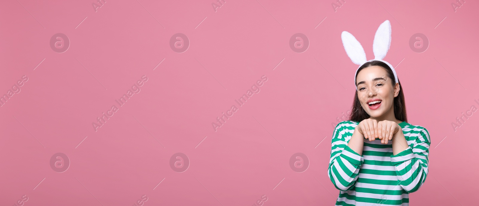 Image of Happy woman with bunny ears headband on pink background, space for text. Easter celebration. Banner design