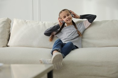 Photo of Girl with headphones sitting on comfortable sofa in living room
