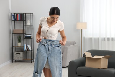 Photo of Young woman with just unpacked new jeans at home, space for text. Online shopping