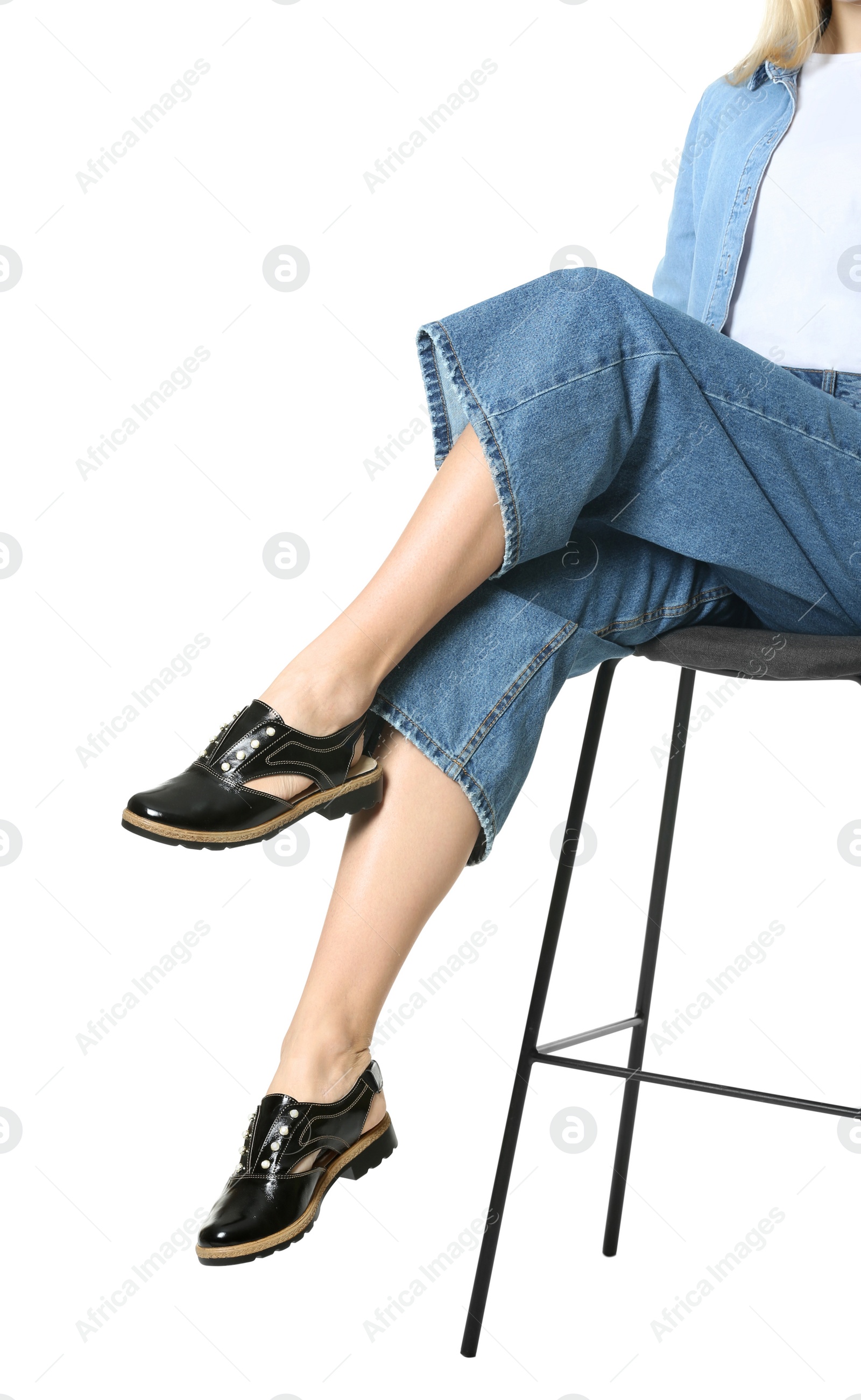 Photo of Woman in stylish shoes on stool against white background, closeup