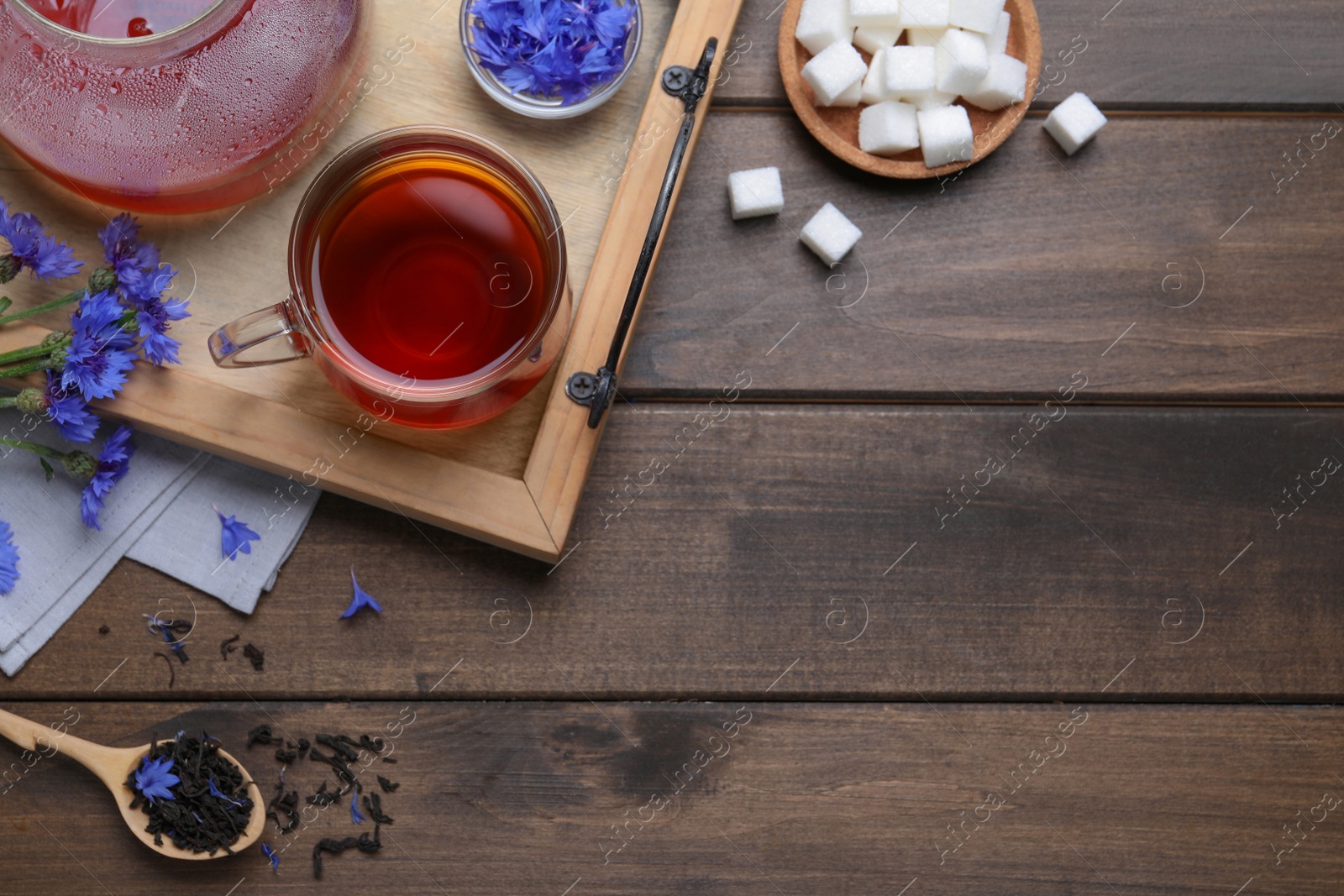 Photo of Composition with tea and cornflowers on wooden table, flat lay. Space for text