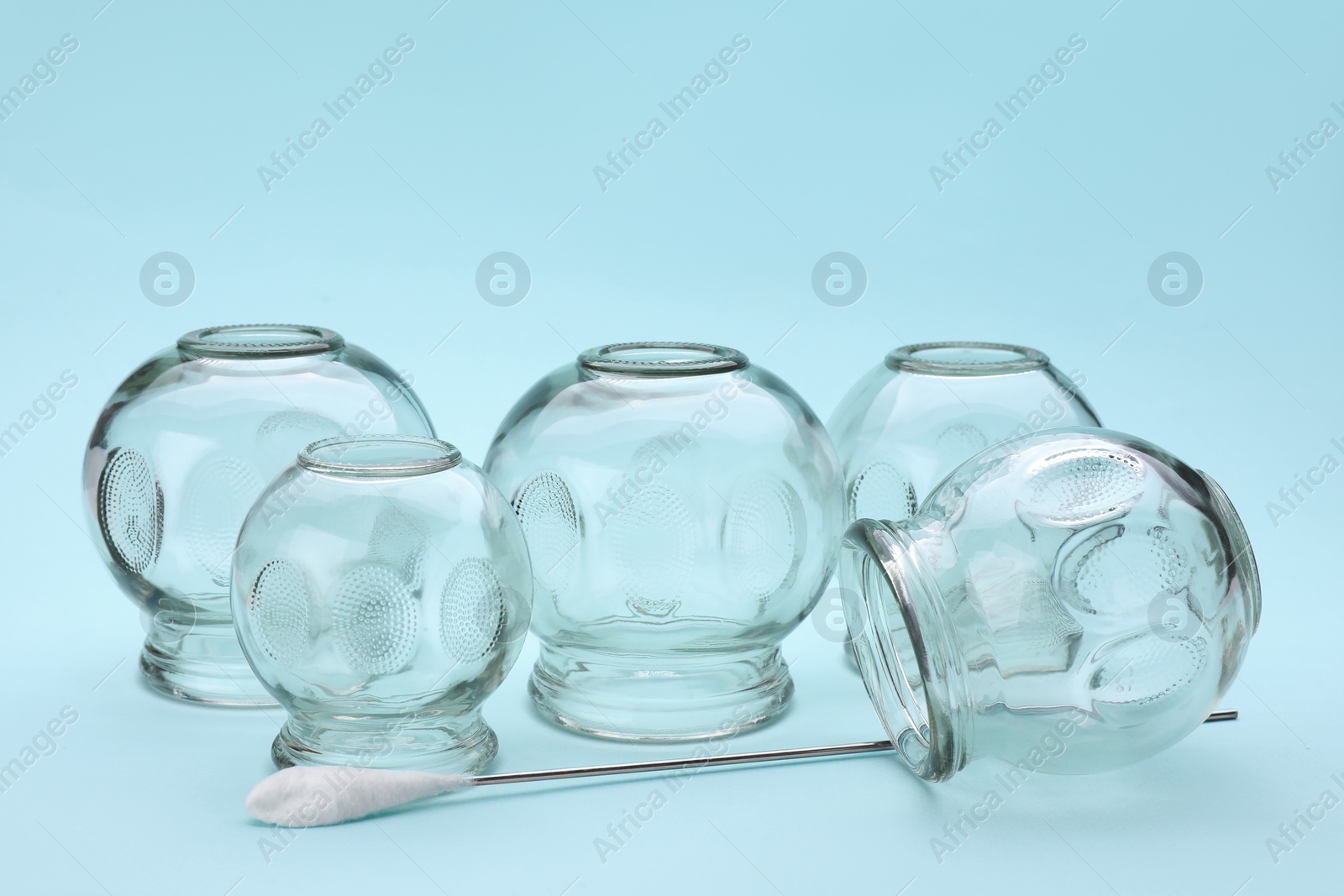 Photo of Glass cups on light blue background. Cupping therapy