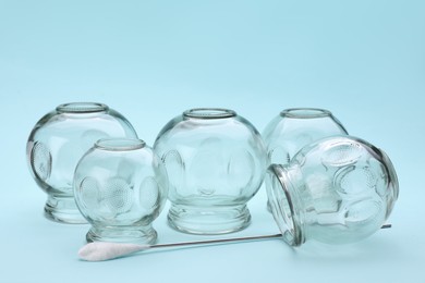 Photo of Glass cups on light blue background. Cupping therapy