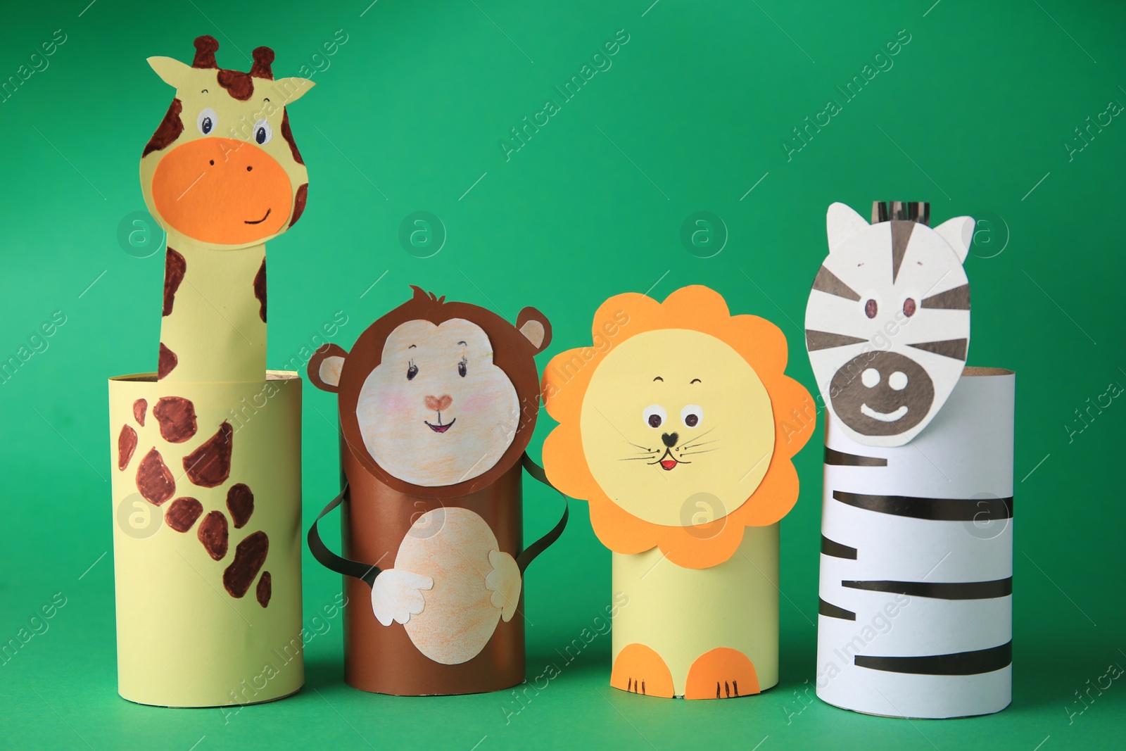 Photo of Toy monkey, giraffe, lion and zebra made from toilet paper hubs on green background. Children's handmade ideas