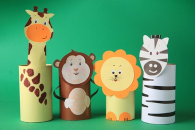 Photo of Toy monkey, giraffe, lion and zebra made from toilet paper hubs on green background. Children's handmade ideas