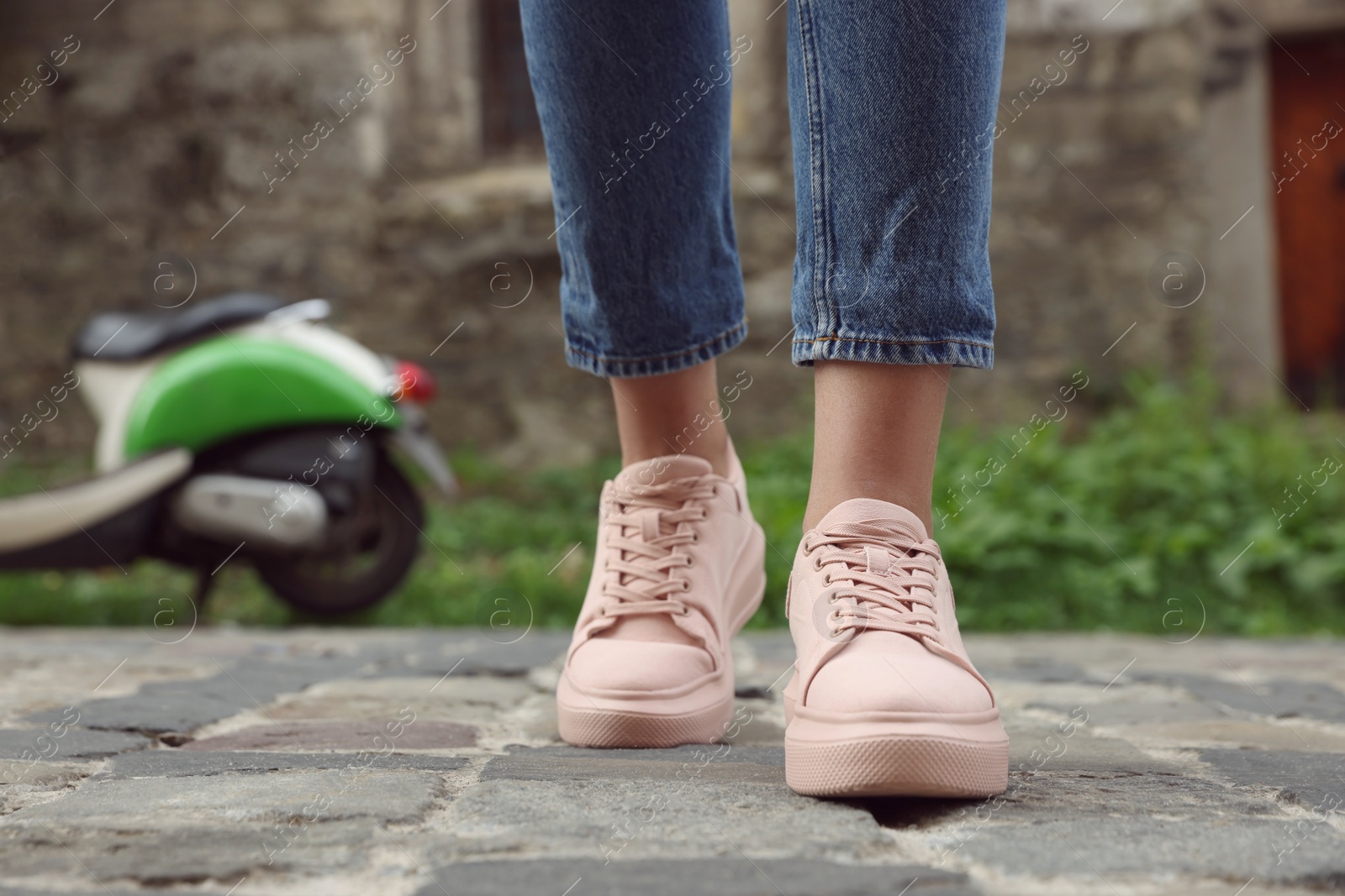 Photo of Woman in stylish sneakers walking on city street, closeup