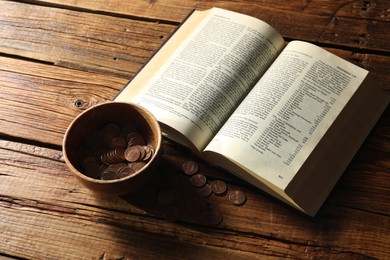 Photo of Donate and give concept. Bowl with coins and Bible on wooden table, above view
