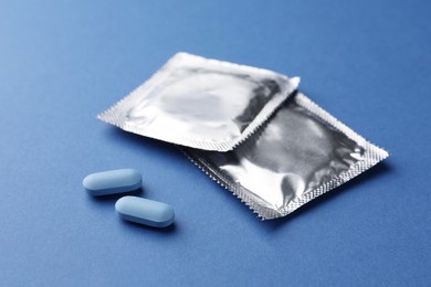 Photo of Pills and condoms on blue background. Potency problem