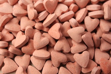 Photo of Heart shaped vitamins for pets as background, closeup