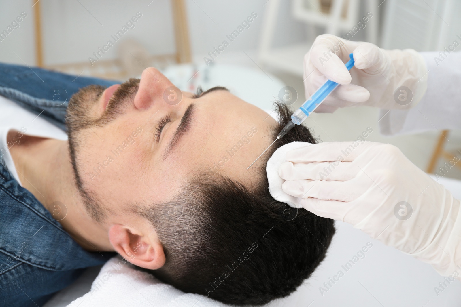 Photo of Man with hair loss problem receiving injection in salon