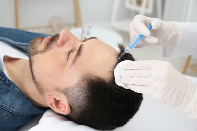 Photo of Man with hair loss problem receiving injection in salon