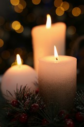 Photo of Beautiful burning candles against Christmas lights, closeup