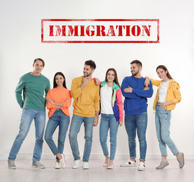 Immigration concept. Group of young people standing near light wall