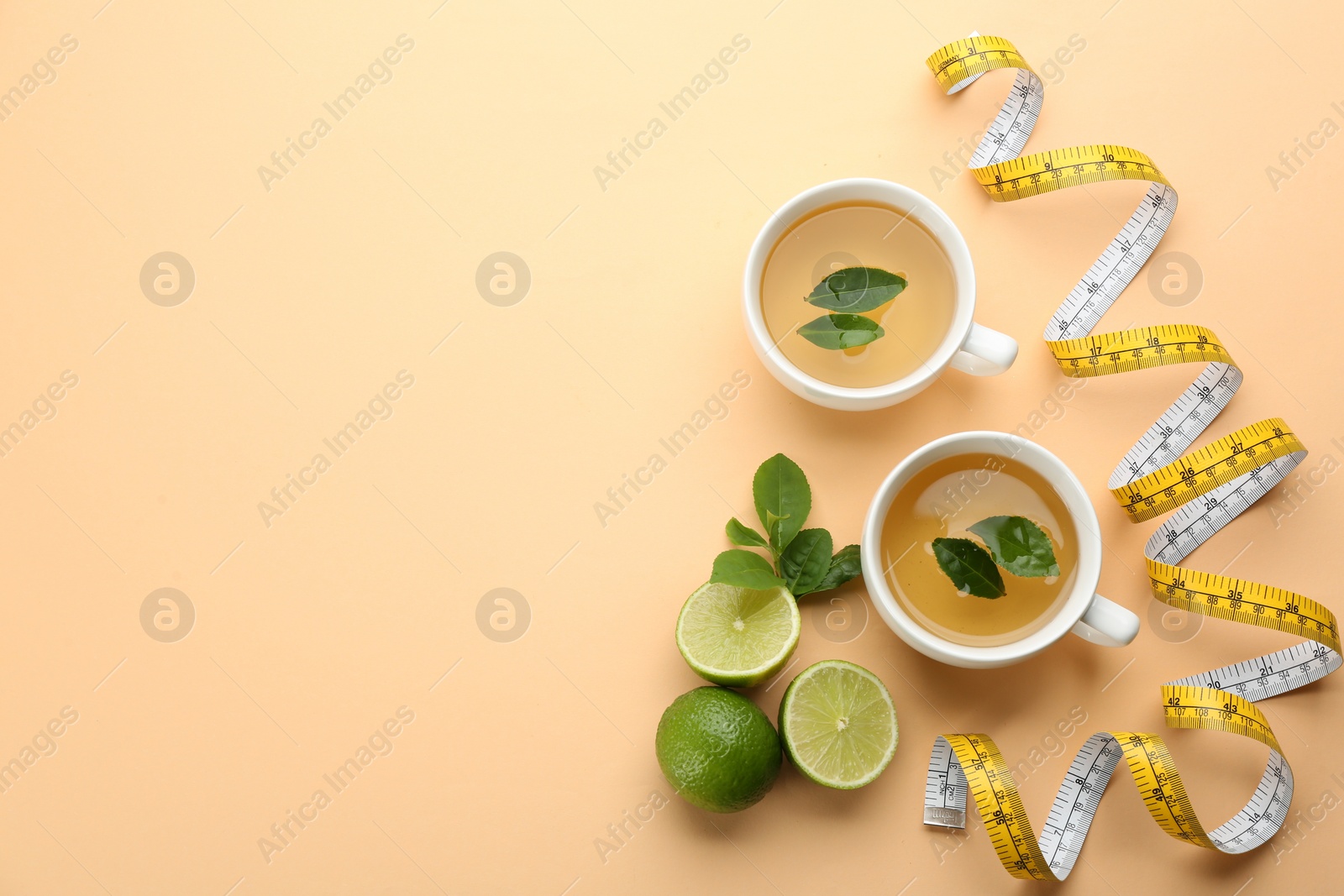 Photo of Flat lay composition with cups of diet herbal tea and measuring tape on orange background, space for text