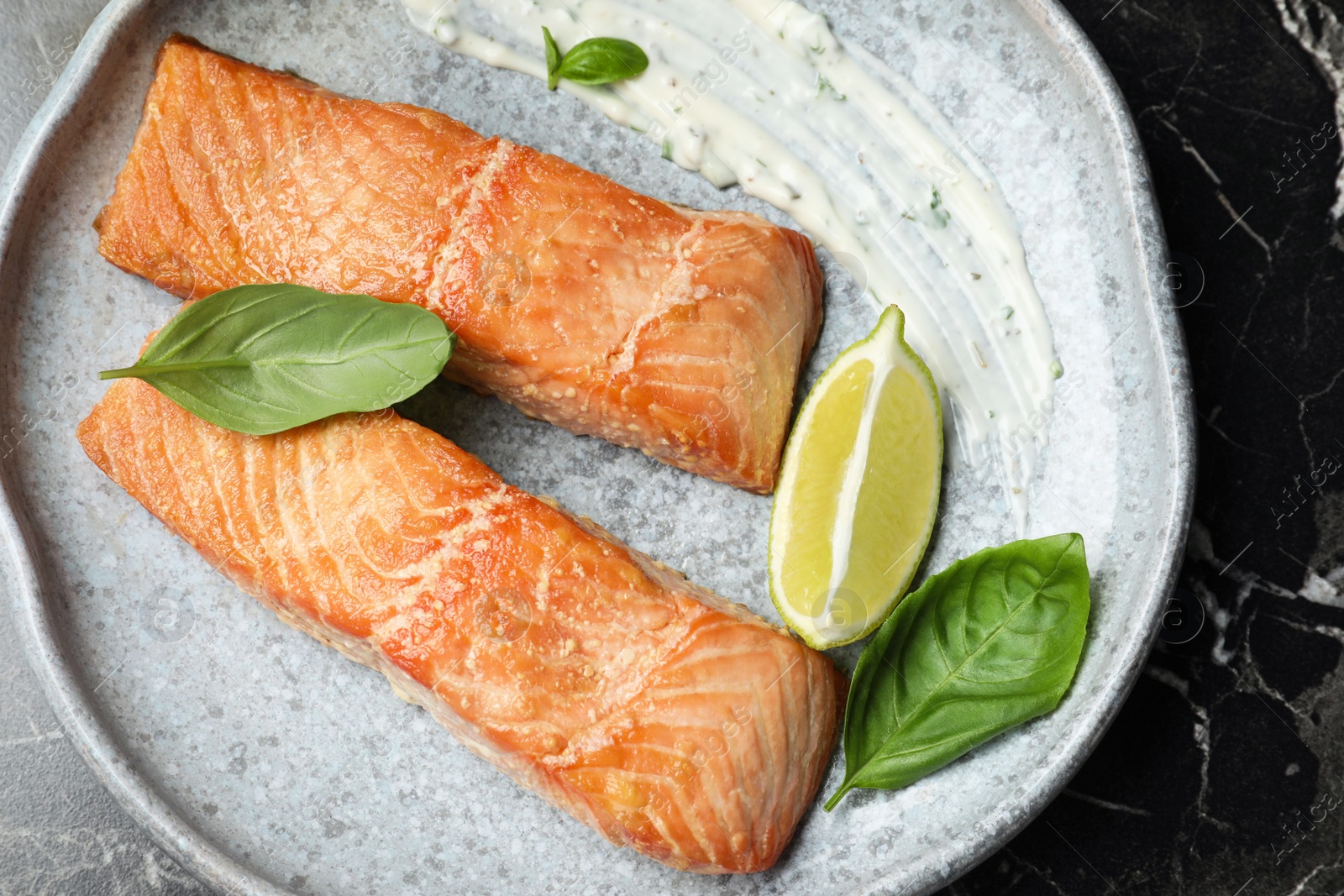 Photo of Tasty cooked red fish on dark grey marble table, top view