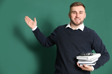 Photo of Portrait of young teacher with books on green background