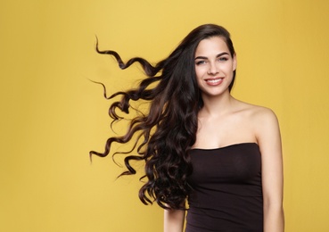 Portrait of beautiful model with gorgeous curly hair on color background