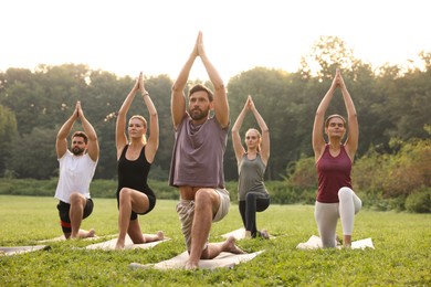 Photo of Group of people practicing yoga on mats outdoors