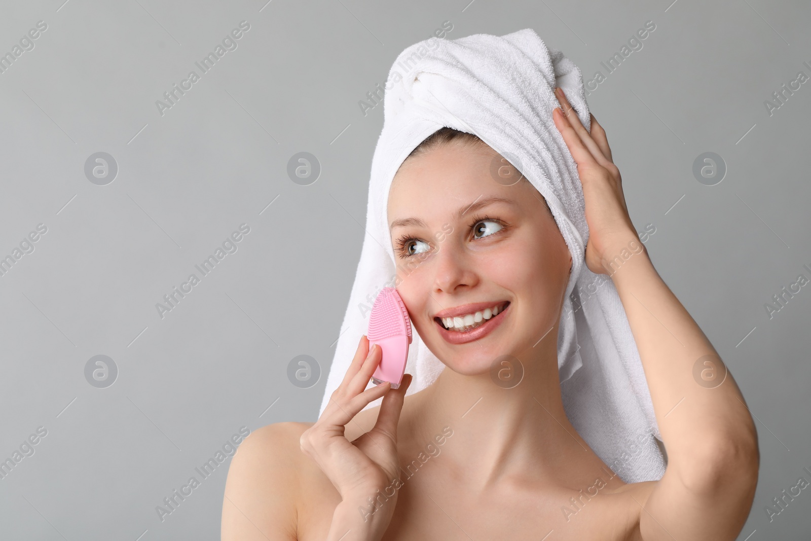 Photo of Washing face. Young woman with cleansing brush on grey background, space for text