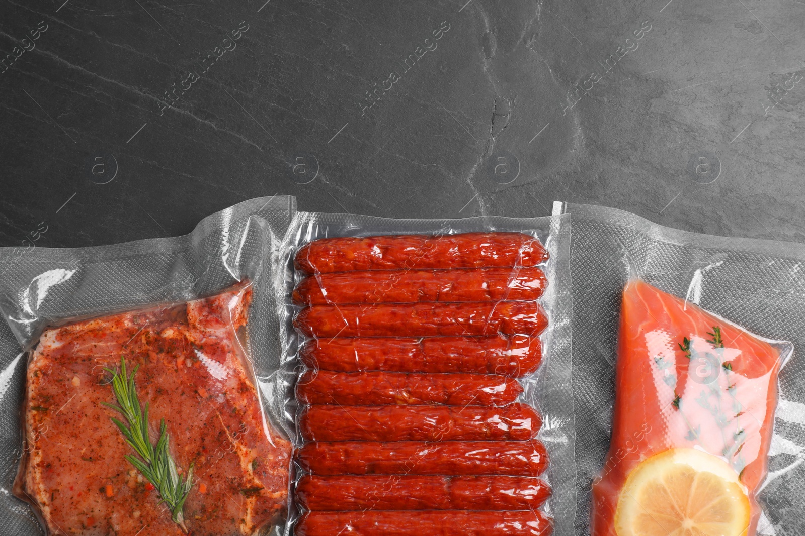 Photo of Tasty food in vacuum packings on dark grey table, flat lay. Space for text