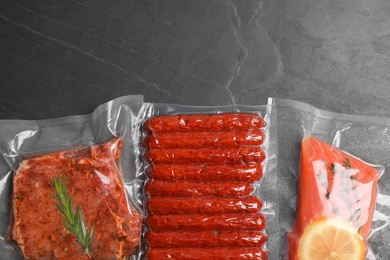 Photo of Tasty food in vacuum packings on dark grey table, flat lay. Space for text