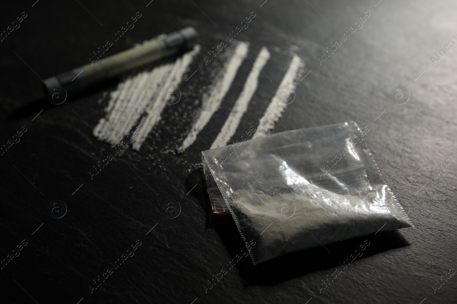 Photo of Drug addiction. Plastic bag with cocaine and rolled dollar banknote on grey textured table, closeup