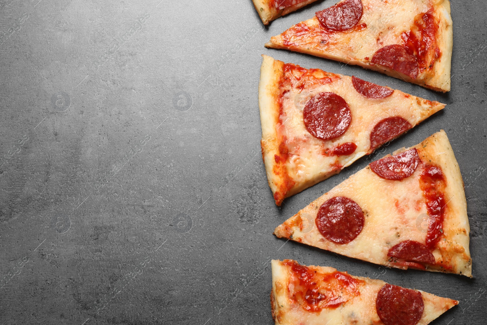 Photo of Slices of hot delicious pepperoni pizza on grey table, flat lay. Space for text