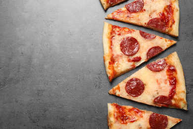 Photo of Slices of hot delicious pepperoni pizza on grey table, flat lay. Space for text