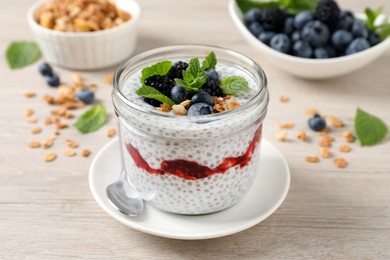 Photo of Delicious chia pudding with berries and granola on wooden table