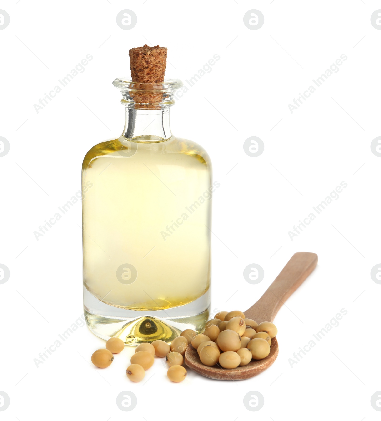 Photo of Glass bottle of oil, wooden spoon and soybeans on white background