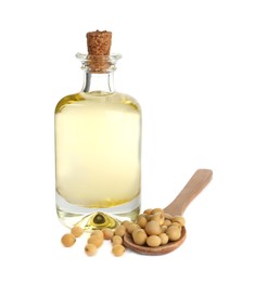 Photo of Glass bottle of oil, wooden spoon and soybeans on white background