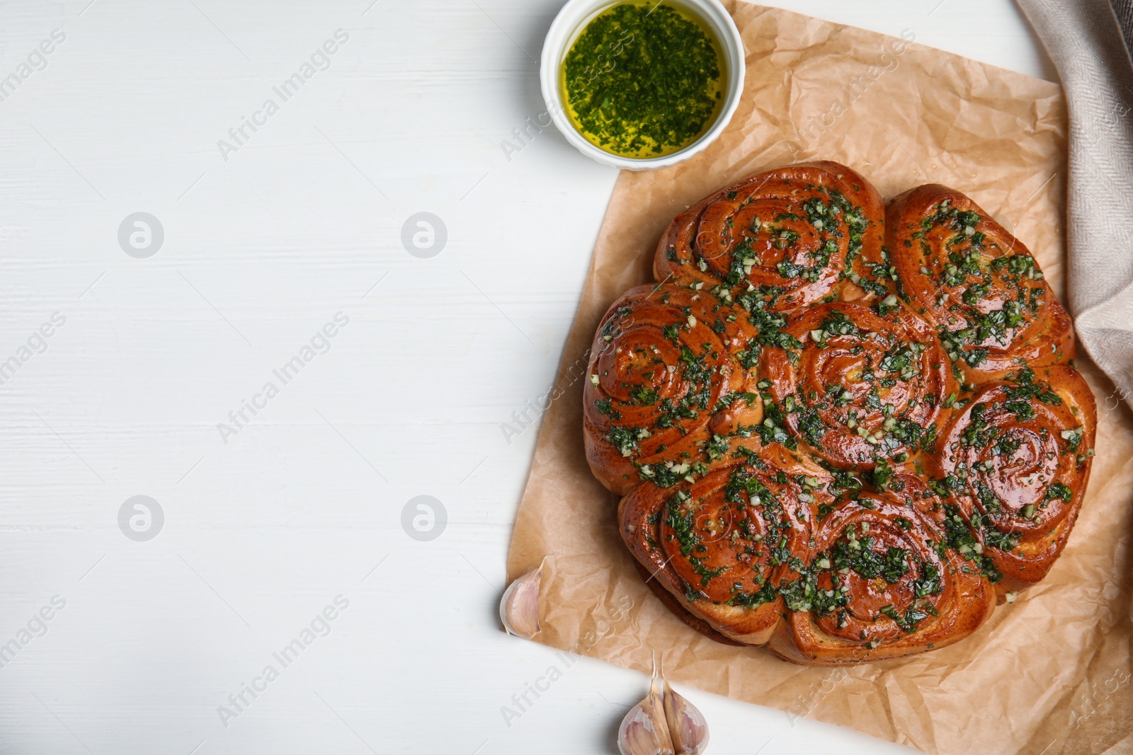 Photo of Traditional Ukrainian garlic bread with herbs (Pampushky) and aromatic oil on white wooden table, flat lay. Space for text.
